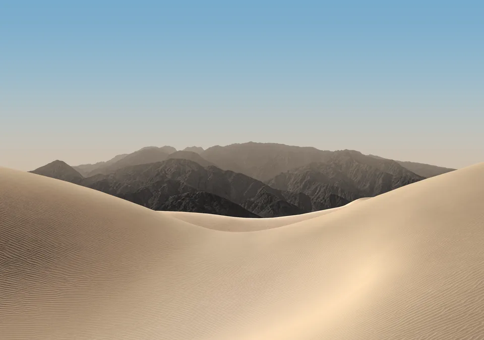 iPhone Duo default inner display Home Screen wallpaper, light version: pale sand dunes and hazy mountains under a soft blue morning sky.